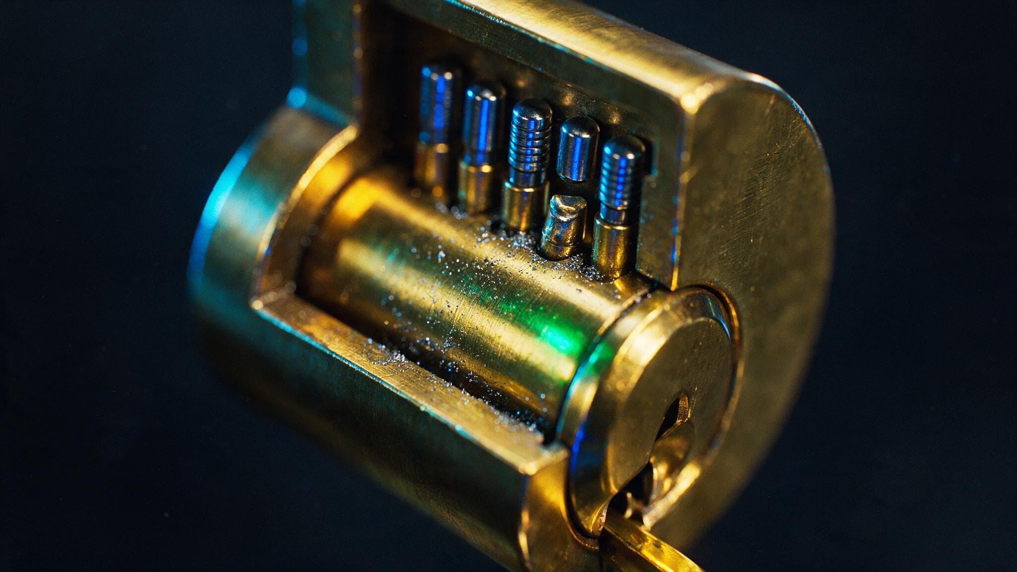 Extreme close-up of a brass lock mechanism in cross-section, its internal pins visibly worn and misaligned so the mechanism no longer seats