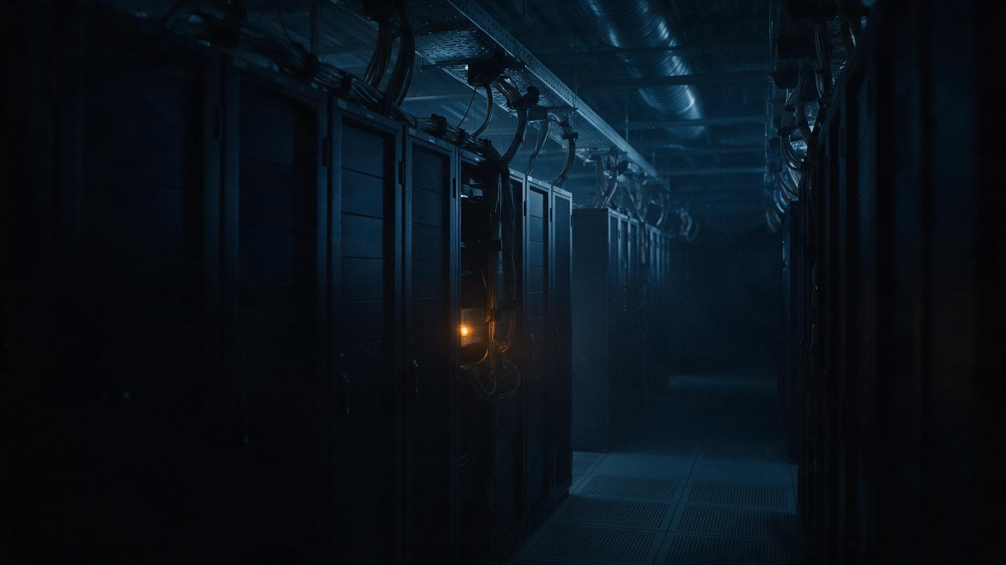 A single amber warning light glowing on one rack unit in an empty dark server room