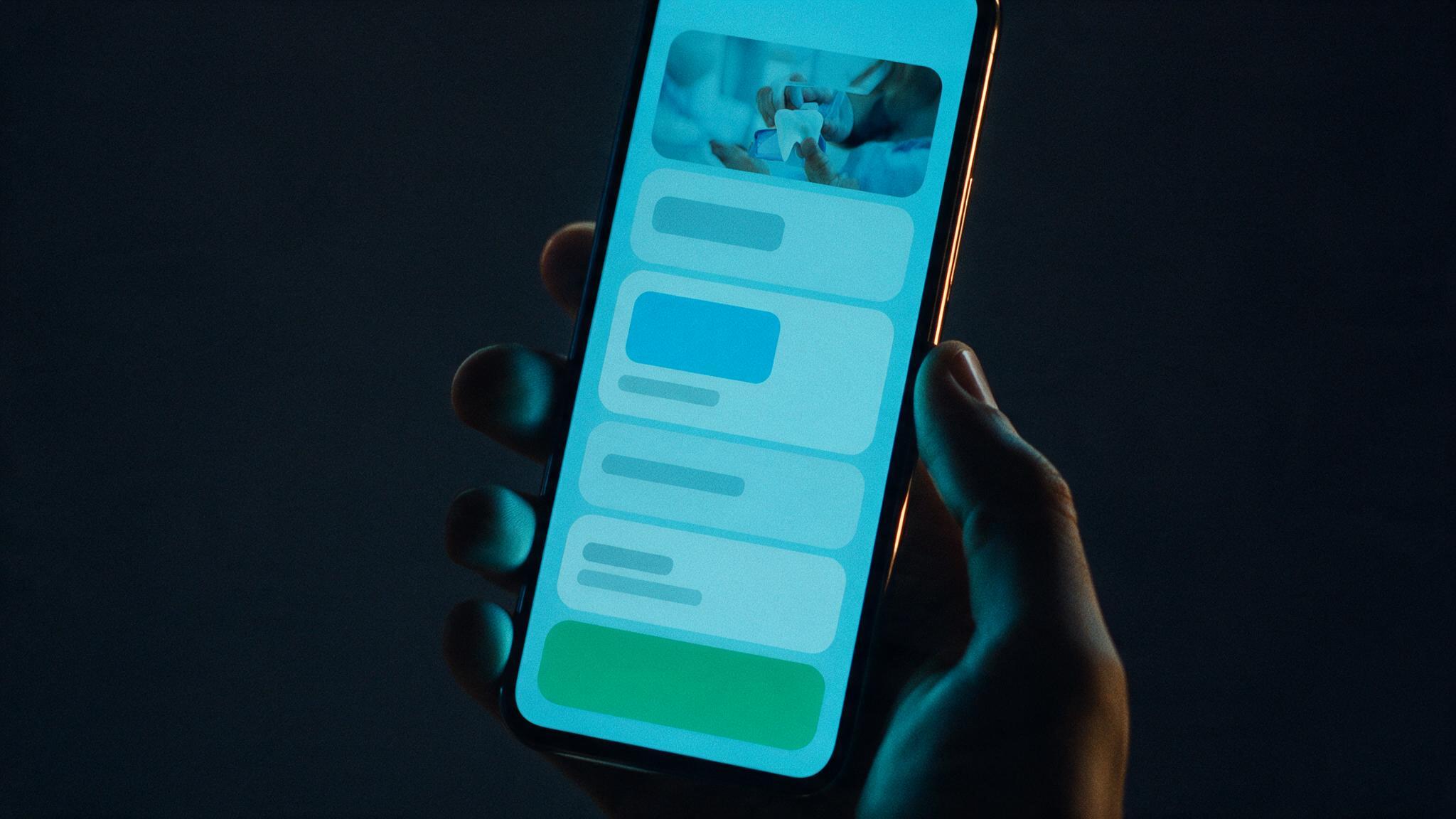 A hand holding a phone showing a dental practice website